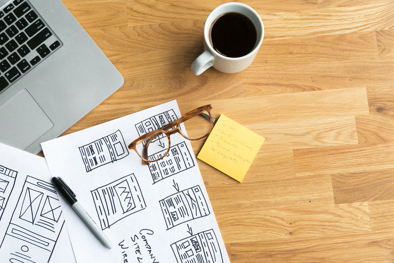 A designer's desk with wireframe sketches and a cup of coffee