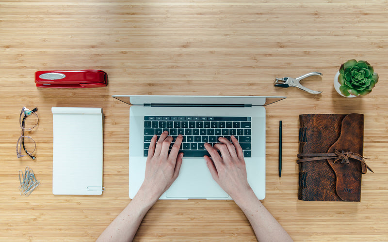 Overhead view of a tidy desk with a notebook, pen and coffee cup