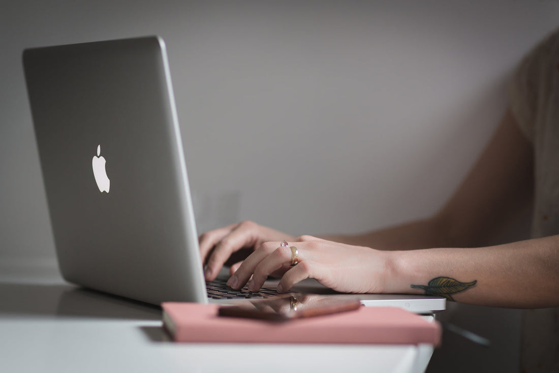 Hands typing on a laptop keyboard at a desk