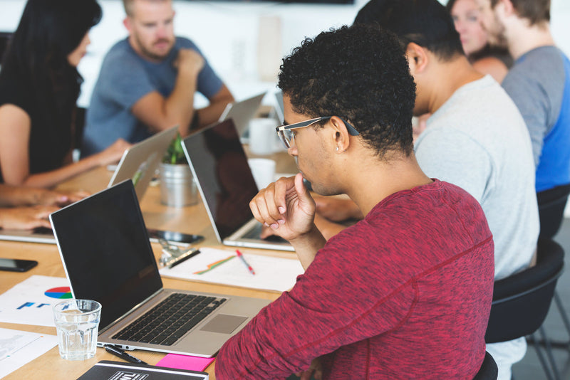 A small team working together around laptops at a shared table